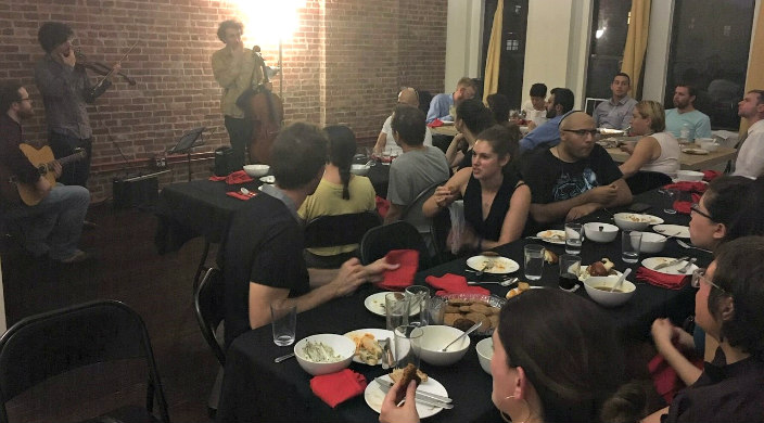 People gathered around dinner tables together while a band plays