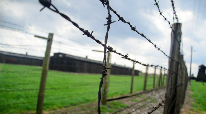 Barbed wire fence in front of Majdanek concentration camp on a sunny day 