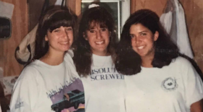Three female campers smiling at the camera in a photo taken at camp in the 1980s