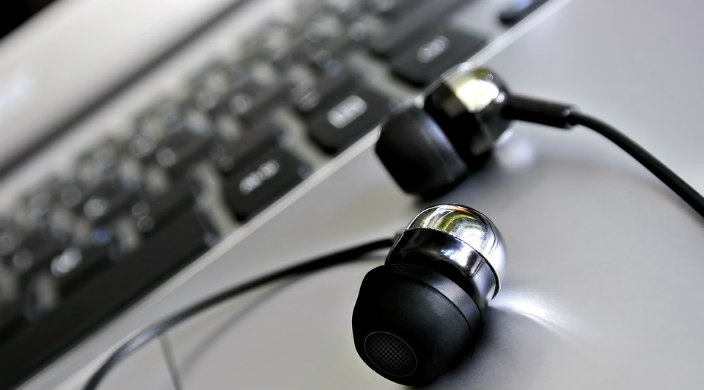 Black and silver earbuds sitting on a laptop keyboard