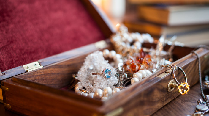 Jewelry box overflowing with shiny jewelry against the backdrop of a modern bedroom