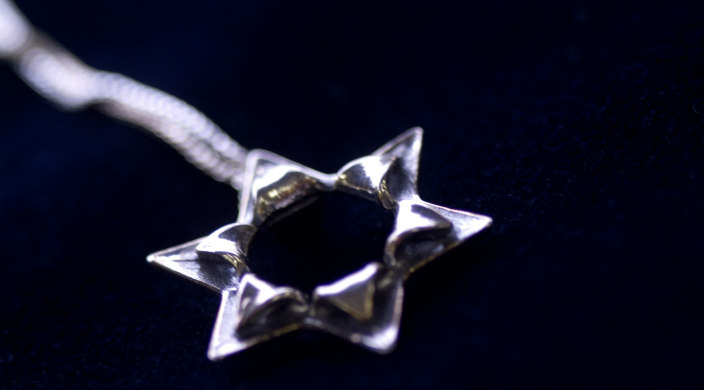 Modern style silver Jewish star on a chain with dark blue/black background