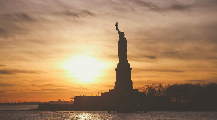 Side view of the Statue of Liberty during an orange sunset