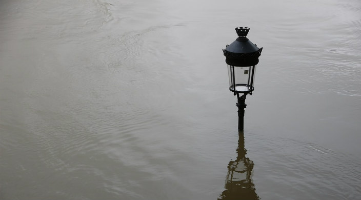 Streetlight peeking out over floodwaters on a flooded street
