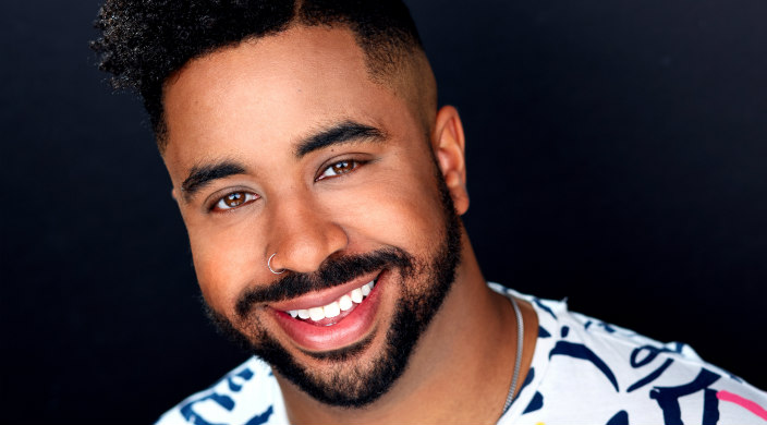 Headshot of a smiling Marques Hollie against a black backdrop 