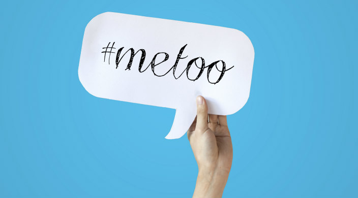 Hand holding a speech bubble that read hashtag metoo inside against a blue background