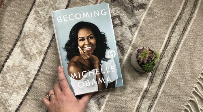 Hand reaching toward Michelle Obamas book Becoming 