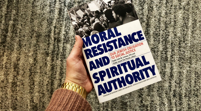 Hand in a pink sweater holding the new Moral Resistance book