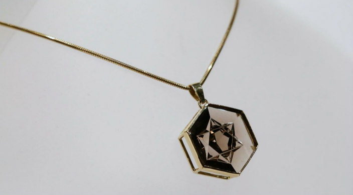 Amber colored crystal pendant engraved with a Star of David on a chain against a white background