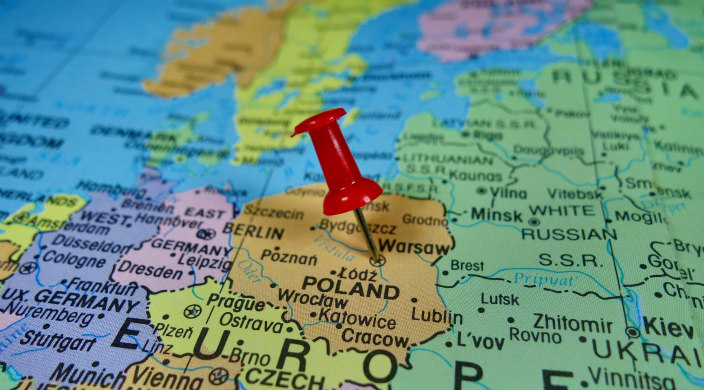 Closeup of a map of Europe with a red pushpin on the country of Poland 
