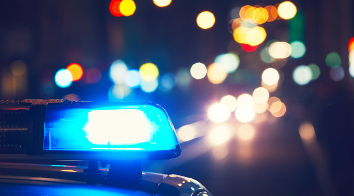 Closeup of a police siren in the dark with colorful but blurry lights  in the distance 