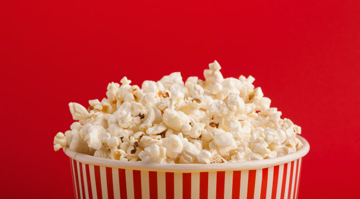 Overflowing bucket of popcorn against a red background