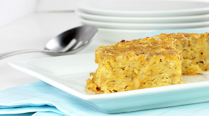 Close up of a slice of potato kugel on a white plate 