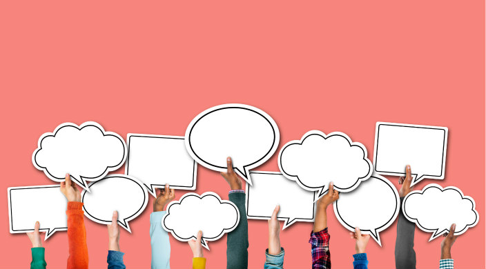 Hands holding up speech bubble signs against a light pink background