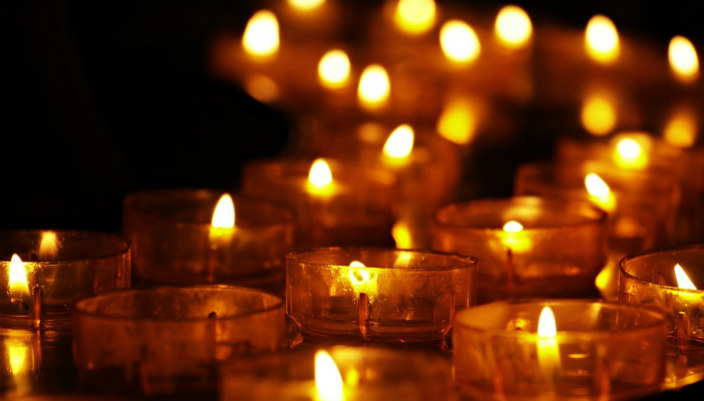 Tea lights lit against a black background as if in mourning