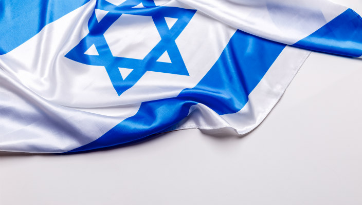 Shiny but rumpled Israeli flag lying upon a white surface 
