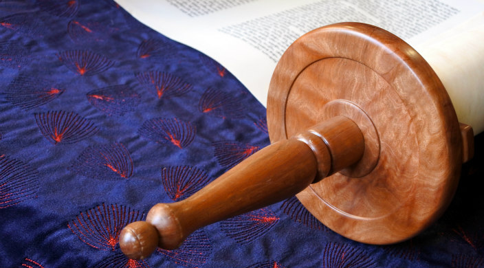 Unfurled Torah lying on a blue fabric with a light red fireworks pattern 