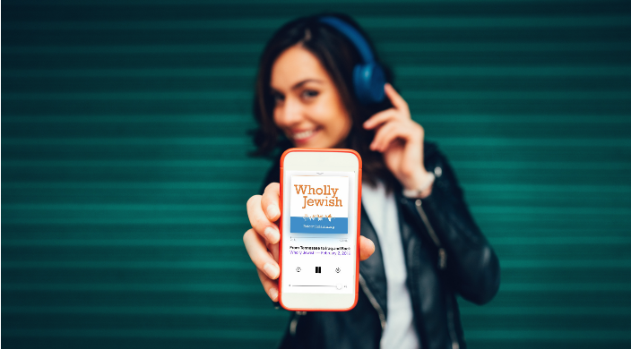 Young woman wearing headphones and listening to Wholly Jewish podcast