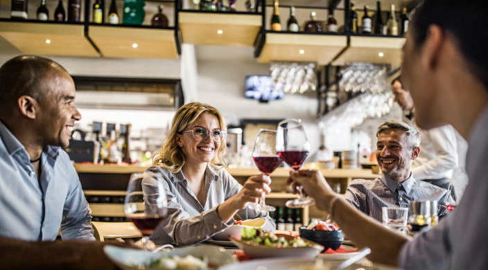 A group of adults eating/drinking in a restaurant or someone's home
