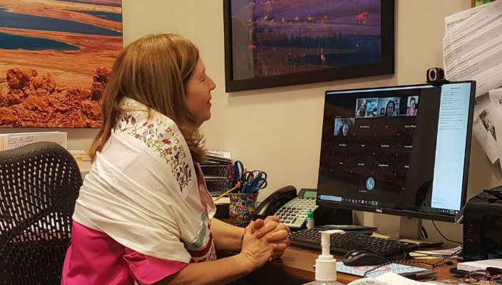 The author sits at her home office while wearing a prayer shawl and speaking on a Zoom call