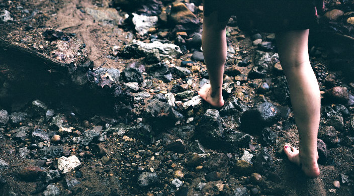 Womans feet barefoot on jagged rocks 