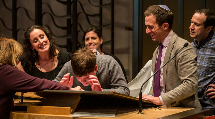 Rabbi Spratt and others working with a bar mitzvah student at the lecturn on the bimah
