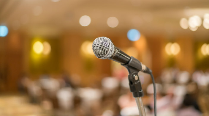 Microphone at the front of a large room; background of photo is blurred