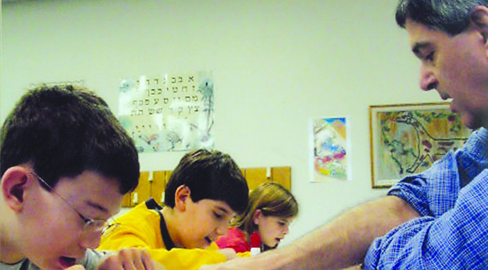 Children studying at a table under the guidance of an adult