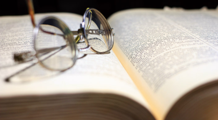 Open dictionary with a pair of reading glasses sitting atop the left hand page