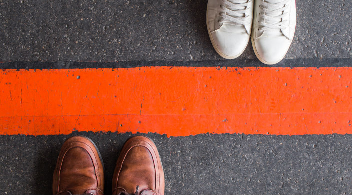 Shoes standing on either side of a red line as if divided or separated 