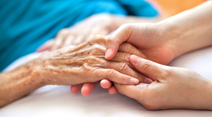 Hand of a young women holding the hand of a young woman as if in a hospital