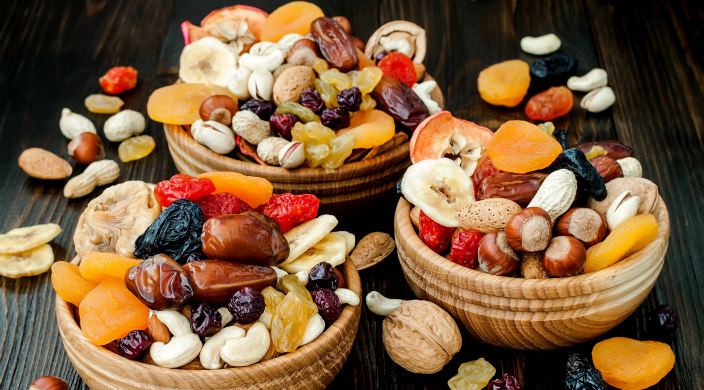 Three wooden bowls filled with dried fruit and nuts