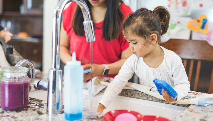 Young girl helping wash the dishes