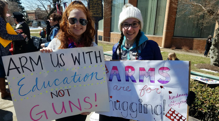 Two high school girls holding gun violence prevention signs at a march