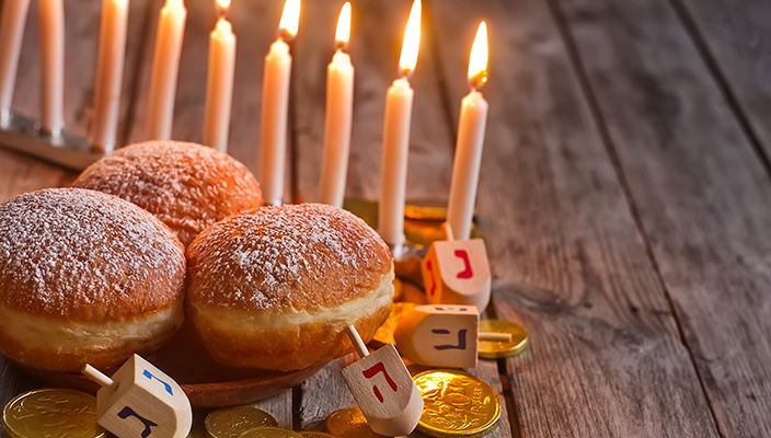 Hanukkah menorah with donuts, dreidels and gelt