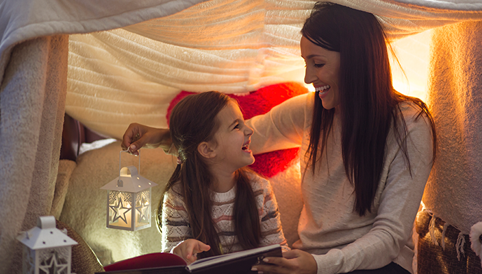 Adult woman and child reading in an indoor tent