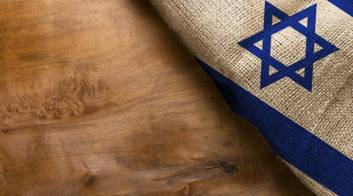 Portion of the Israel flag (Star of David on white background with part of the blue stripes visible) on the righthand part of a wooden surface