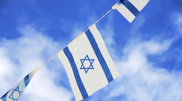 Row of Israeli flags against background of blue sky and clouds 