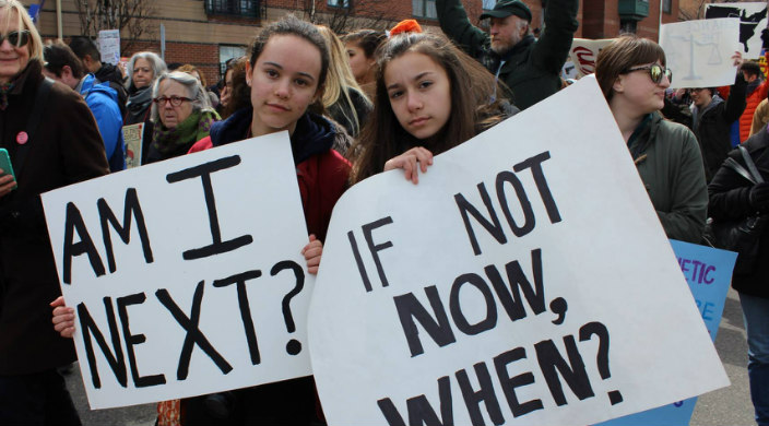 Two young women holding signs protesting gun violence