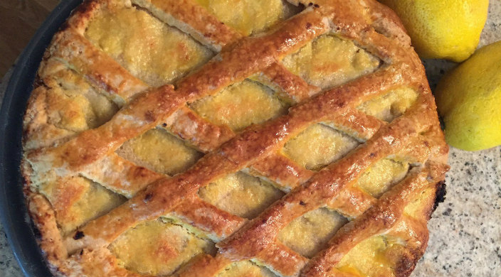 Lattice-topped lemon cake on the counter; two fresh lemons alongside the pan