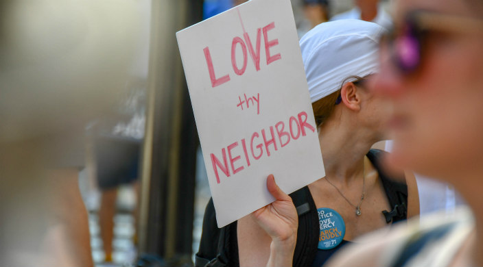 Protester holding a sign that says: Love thy Neighbor