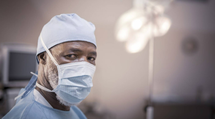 Somber male doctor looking over his shoulder while wearing scrubs and a face mask