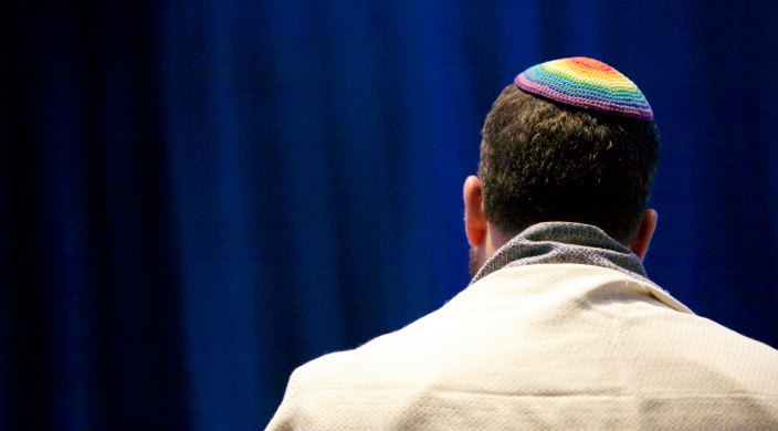 Man facing away from the camera wearing a kippah and prayer shawl