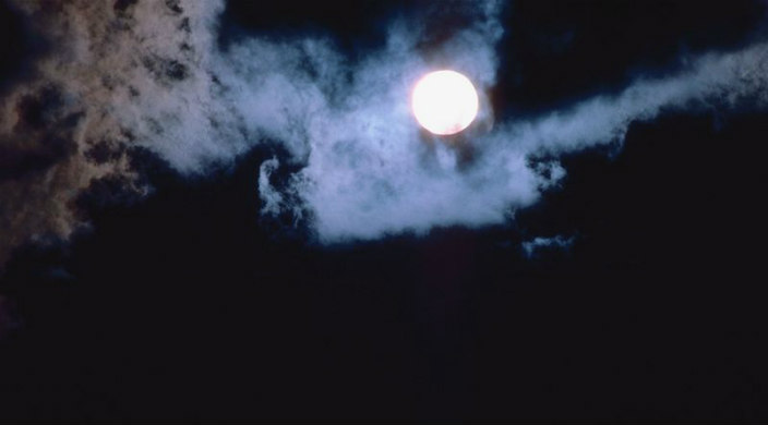 Full moon illuminating dark sky and clouds