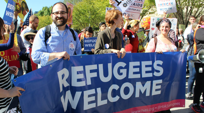 Activists holding a large sign that reads REFUGEES WELCOME