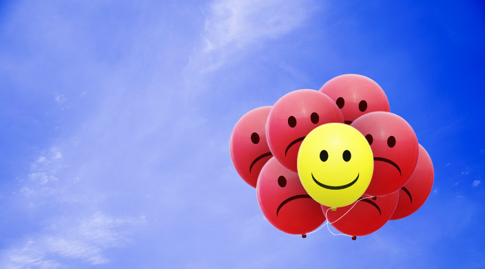 Cluster of balloons with frowning faces and one with a smiley face