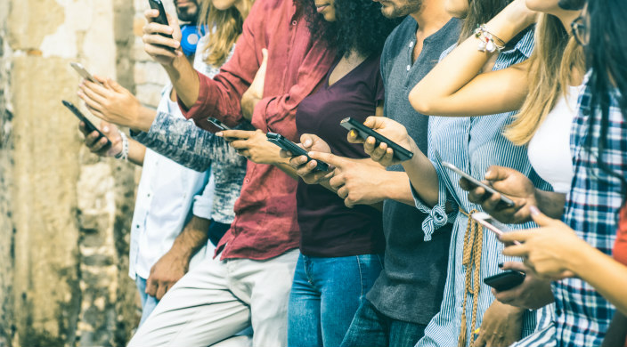 A line of young people all reading from their cell phones