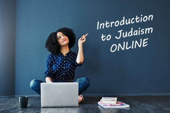 Woman sitting at laptop pointing to chalkboard that says Introduction to Judaism Online