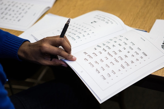 person writing in a Hebrew workbook