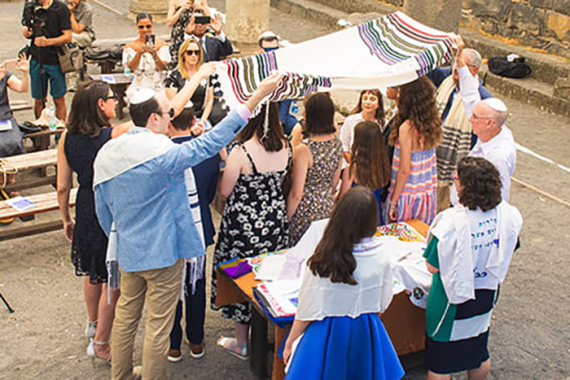 an image of people standing under and around a tallit